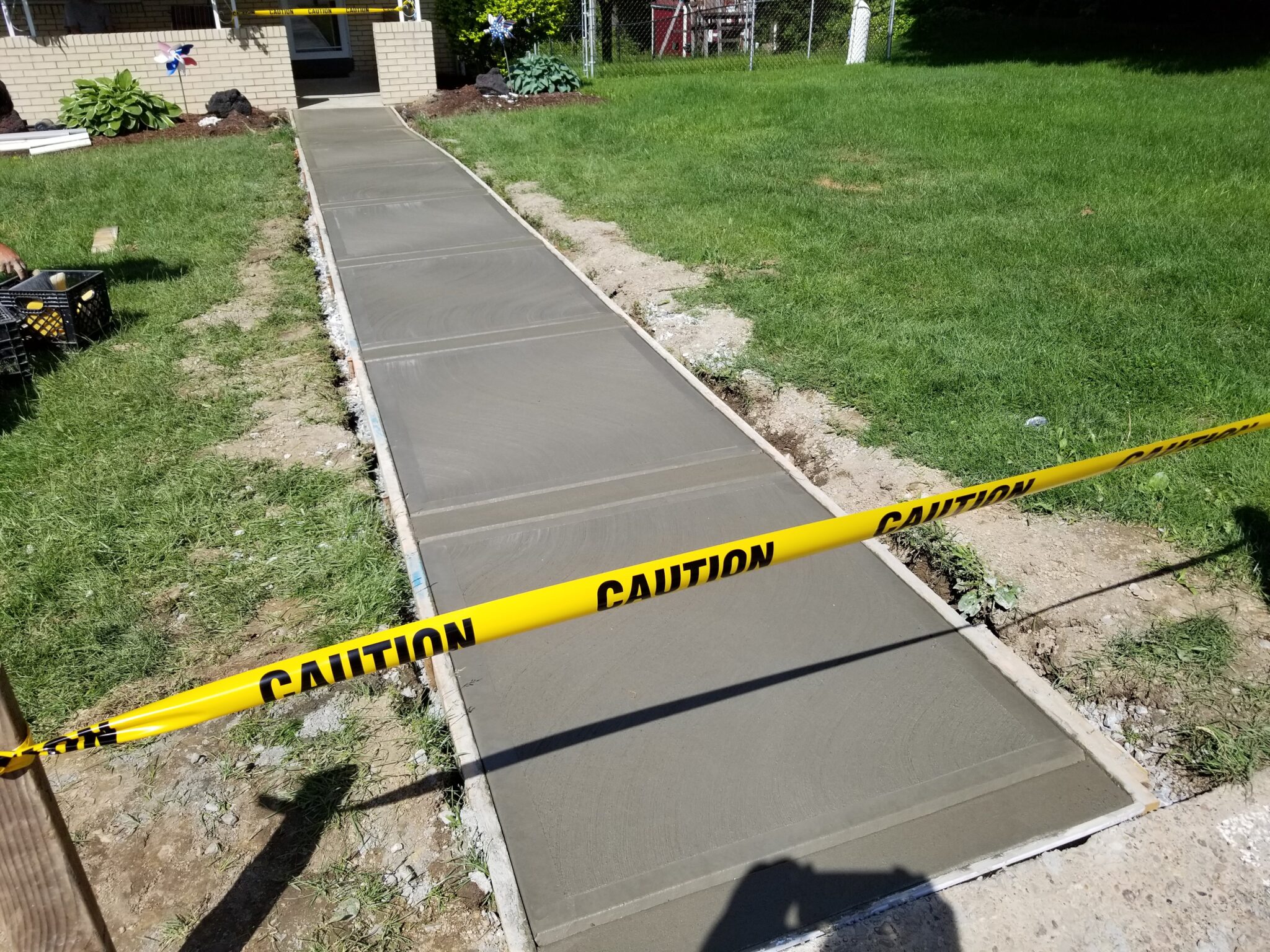 A concrete walkway with caution tape around it.