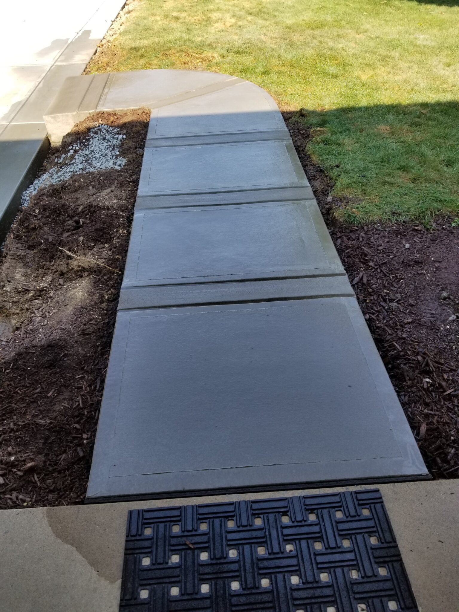 A walkway with a black tile floor and grass
