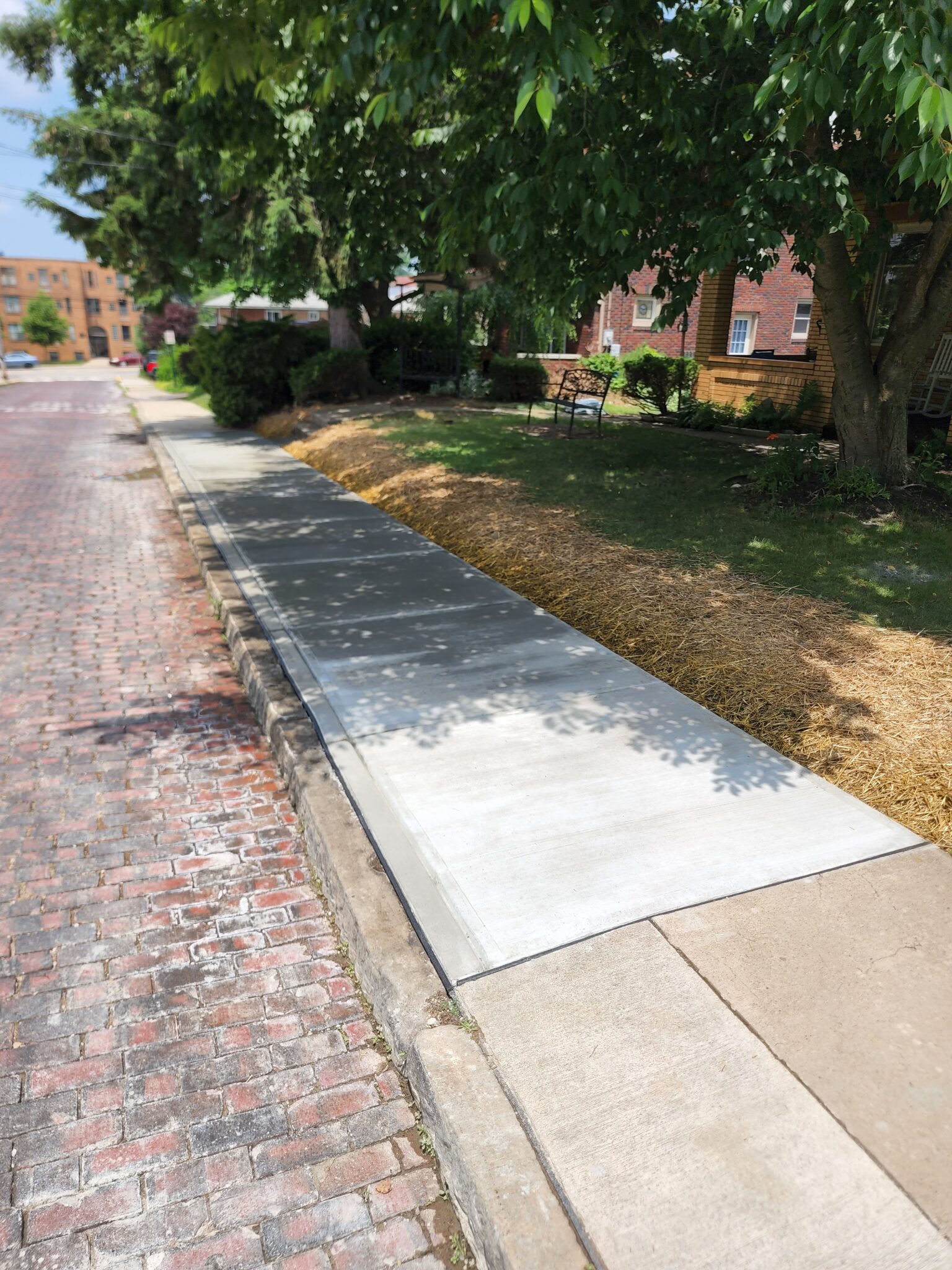 A sidewalk with concrete and brick on the side of it.