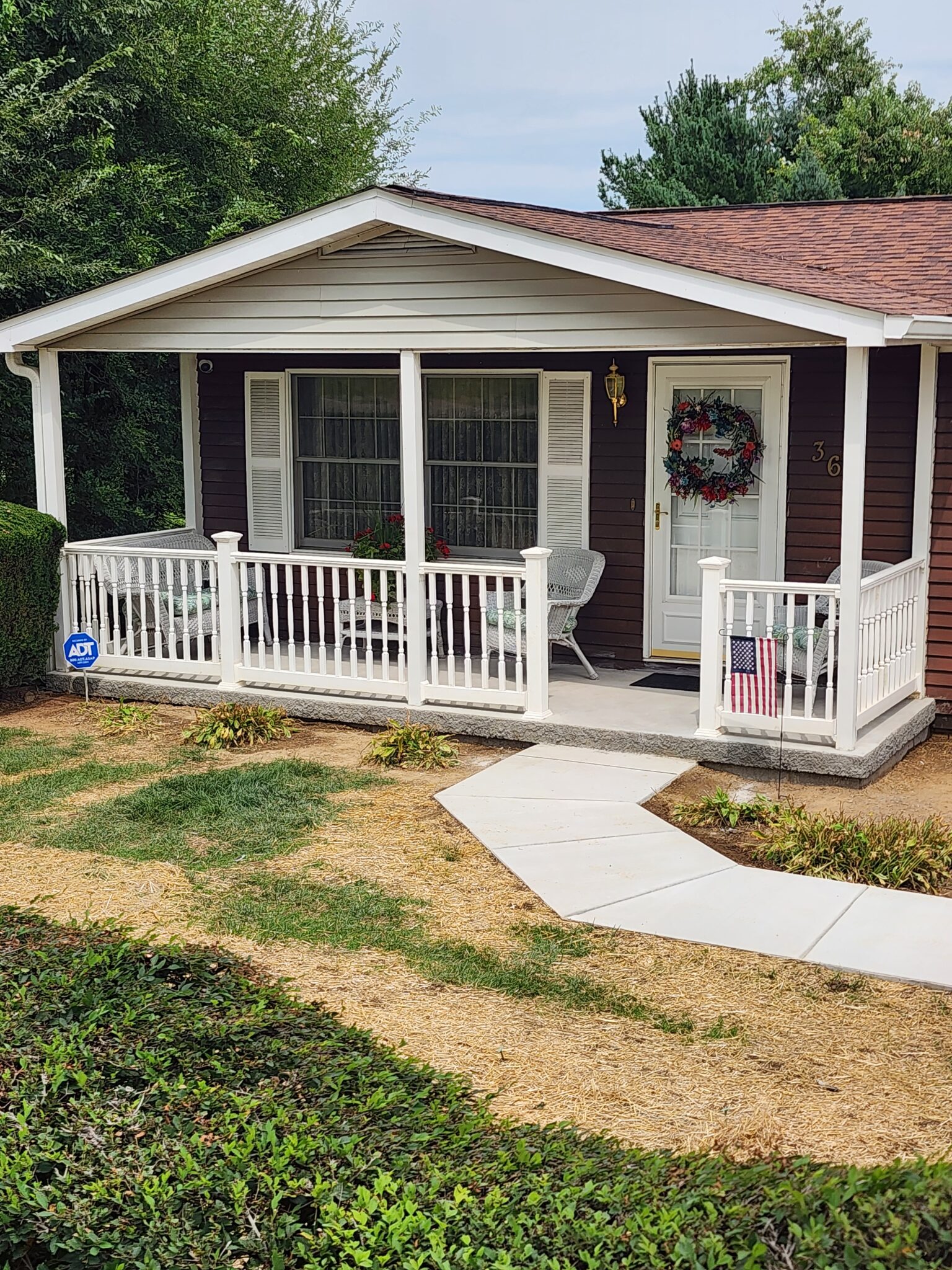A small house with a porch and lawn.