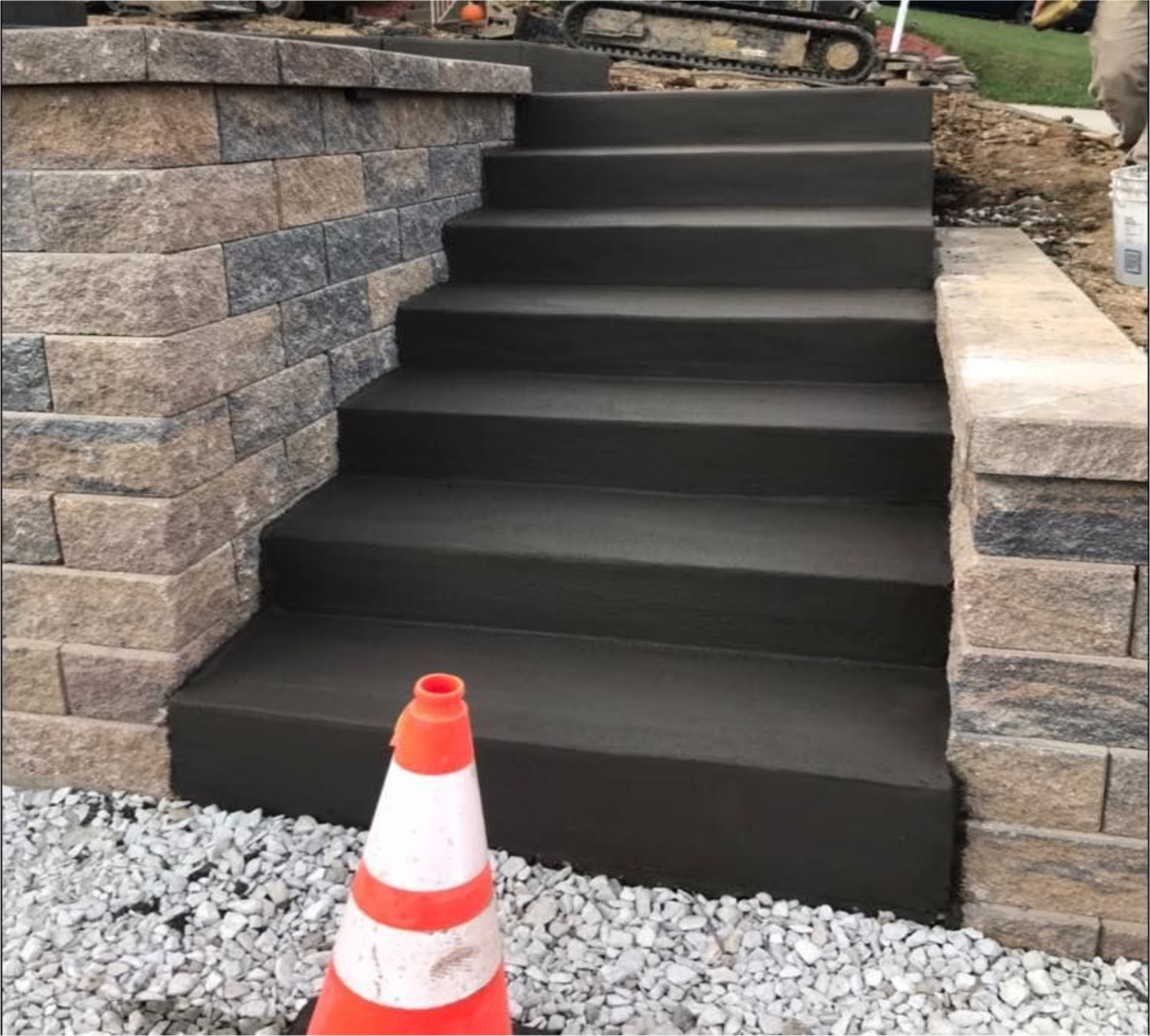 A construction cone sitting on the ground near stairs.