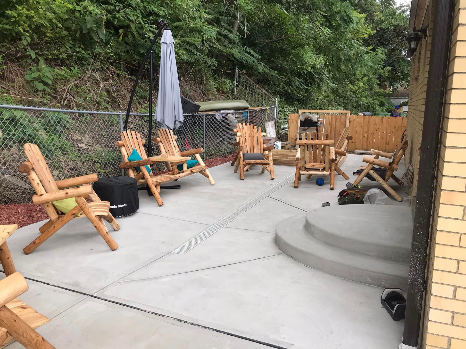 298099327_1919918744878043_4748337005368167087_n-1920w A patio with wooden chairs and an umbrella.
