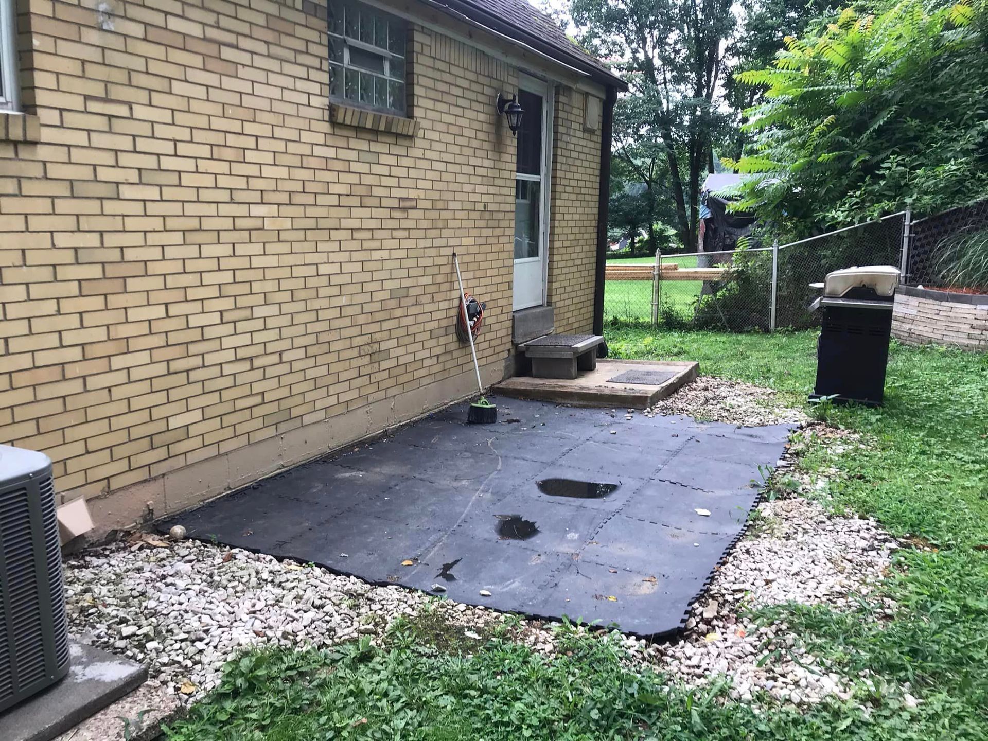 298412080_1919918701544714_7738808629365976671_n-1920w A black tile patio in the middle of a yard.