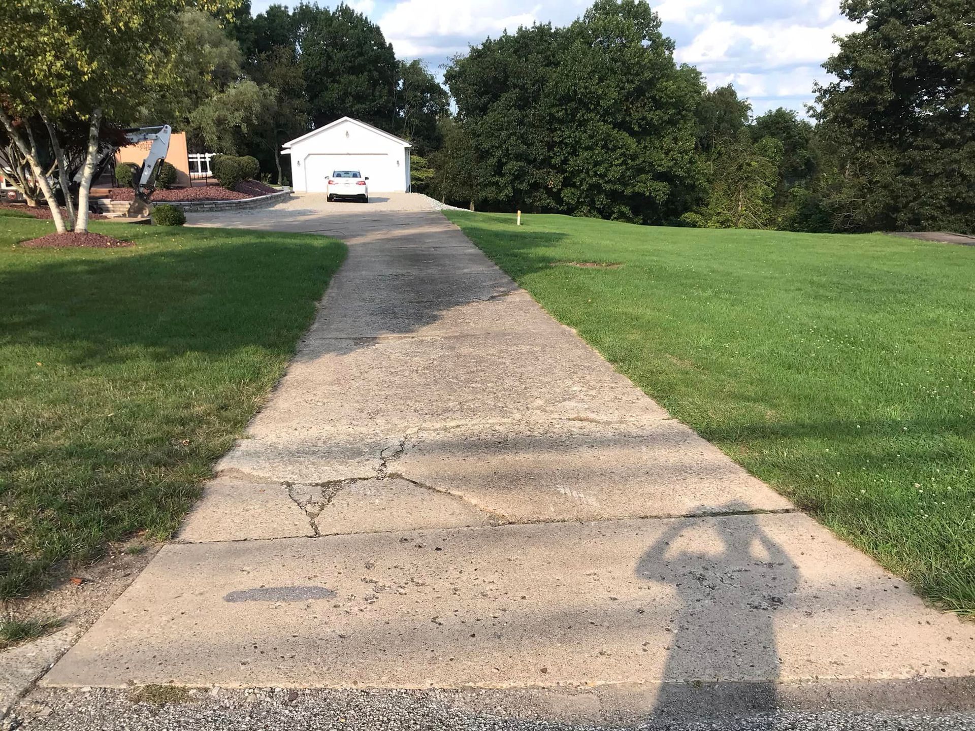 A person is standing on the sidewalk of a driveway.