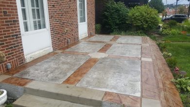 A patio with concrete and brick flooring.