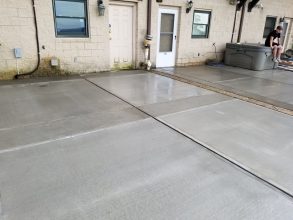 A concrete driveway with two doors and no one in it.