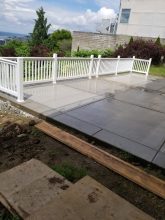 A patio with a wooden deck and white railing.