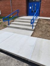 A blue railing and steps leading to the entrance of a building.