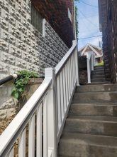A white railing and steps leading up to a brick building.