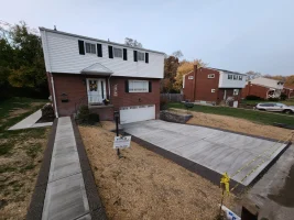 A house with concrete driveway and sidewalk in front of it.