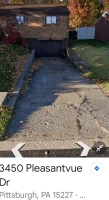 A sidewalk with a broken concrete path and leaves on the ground.