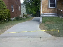 A sidewalk with yellow tape blocking off the entrance to a house.