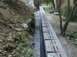 A long wall of concrete is in the middle of a garden.
