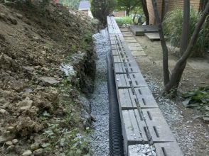 A long wall of concrete is in the middle of a garden.
