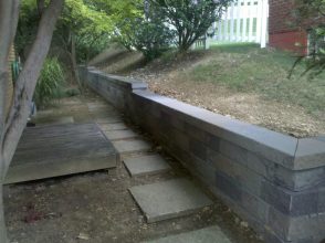 A concrete block wall with steps leading to the ground.
