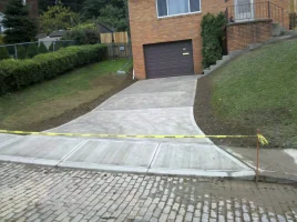 A driveway with yellow tape around it and grass growing on the side.