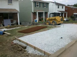 A yellow skid steer is parked on the side of a road.
