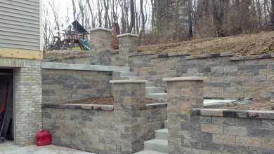 A stone wall with steps and pillars in the middle of it.
