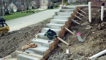 A cement staircase being built on the side of a road.