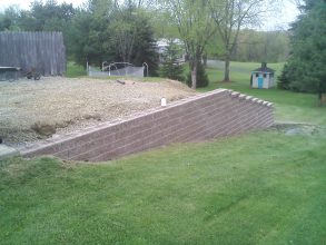 A large concrete block wall in the middle of a yard.